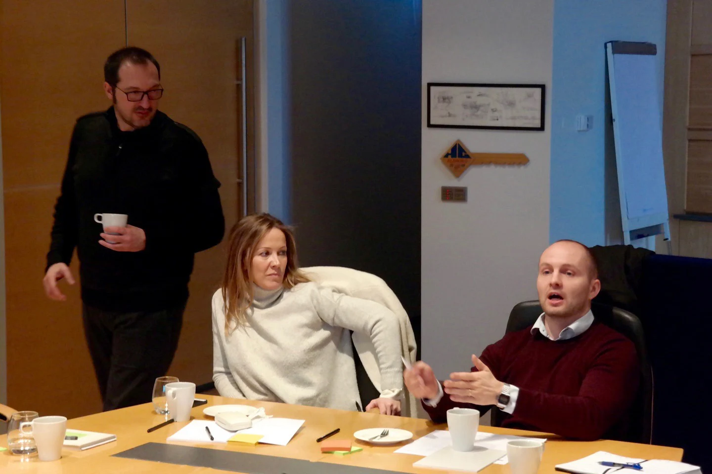 A workshop discussion around the table, with notes and sketches on the wall